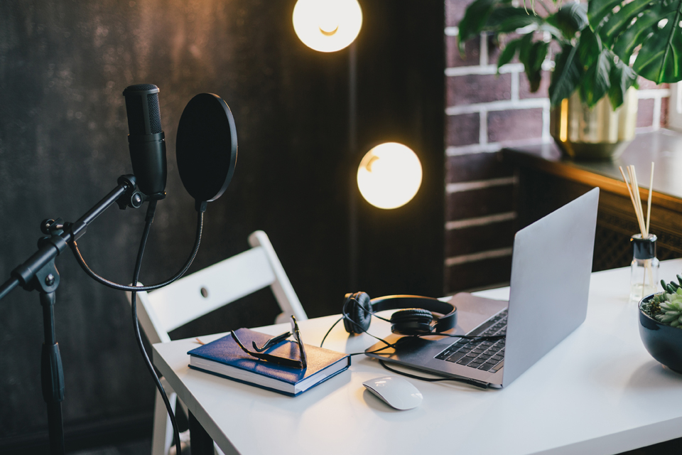 a microphone, laptop, headphones, set up at a desk