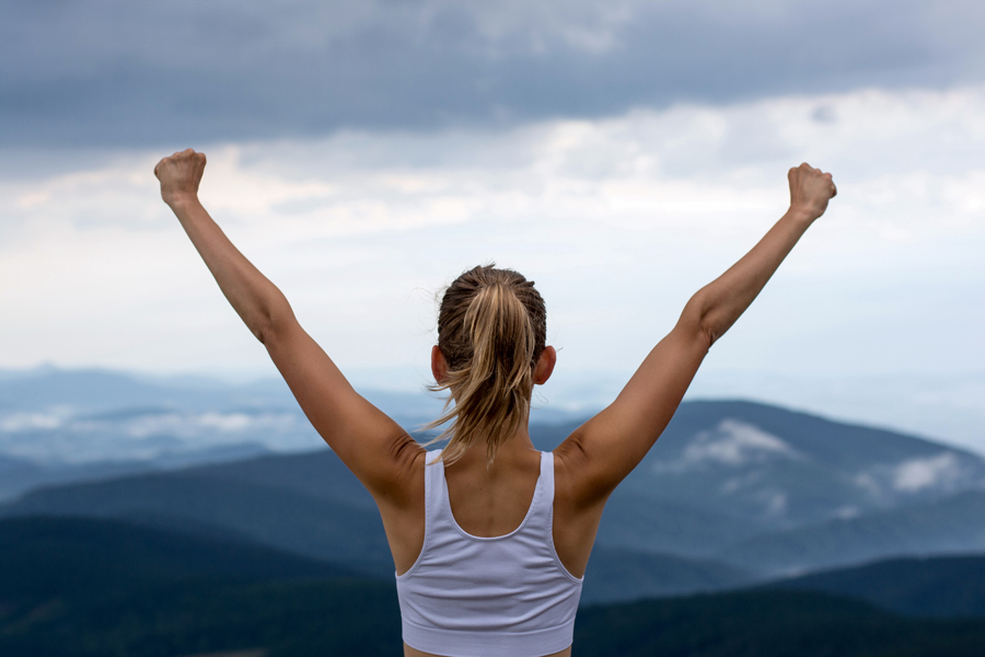 woman standing victorious on top of mountain